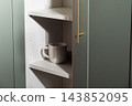 Coffee mug in home cabinet shelf 143852095