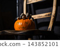 Halloween pumpkin on wooden rickety chair with creepy shadows 143852101