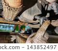 Hand in work gloves using a ratchet wrench to loosen the drain plug, allowing old engine oil to flow out during vehicle maintenance and repair in a garage. 143852497