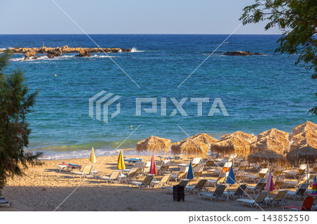 Straw Beach Umbrellas and Sun Loungers on Sandy Beach in Chania Crete Greece 143852550