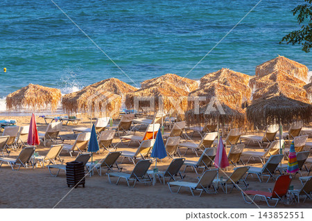 Straw Beach Umbrellas and Sun Loungers on Sandy Beach in Chania Crete Greece Straw Beach Umbrellas and Sun Loungers on Sandy Beach in Chania Crete Greece 143852551