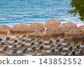 Straw Beach Umbrellas and Sun Loungers on Sandy Beach in Chania Crete Greece 143852552