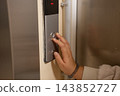 A blind woman presses a button with Braille in an elevator. 143852727