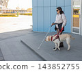 A blind woman with a guide dog is exiting the metro. 143852755