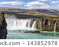 Godafoss waterfall and turquoise currents below snow-streaked hills in North Iceland 143852978