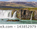 Godafoss waterfall and turquoise river beside rugged cliffs in North Iceland 143852979