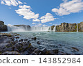 Godafoss waterfall and rushing turquoise river from a low rocky bank in Iceland 143852984