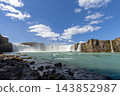 Low view of Godafoss waterfall and turquoise river over a rocky foreground 143852987