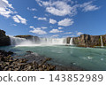 Godafoss waterfall from a low rocky shore beneath a bright summer sky in North Iceland 143852989