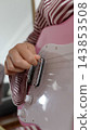 Close-up of a hand picking the strings of a pink electric guitar 143853508