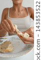 Woman tearing a bread roll over a floral breakfast plate 143853522