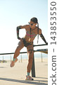 Woman holding a bent-leg warmup by a railing 143853550