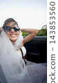Bride in sunglasses smiling from a car passenger seat 143853560