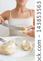 Woman spreading a soft topping on bread with a table knife 143853563