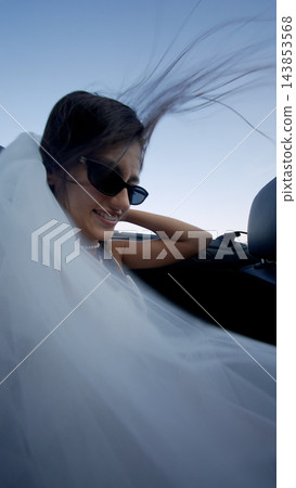 Smiling bride in a white veil beside a car seat Smiling bride in a white veil beside a car seat 143853568