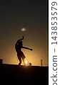 Woman's silhouette with arms extended against a golden sunset 143853579