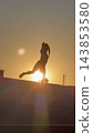 Silhouette of a woman balancing with one leg raised before the setting sun 143853580