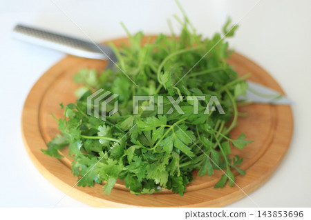 Fresh parsley and kitchen knife on wooden board Fresh parsley and kitchen knife on wooden board 143853696