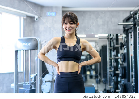 一位年輕女性，經常健身，對自己健美的身材充滿自信；她下班後會去健身房；頭髮顏色正常，中間部分修剪過。 143854322