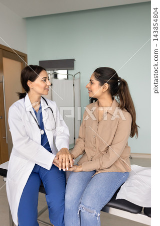 Positive Middle Eastern doctor holding hands of young Indian patient 143854804