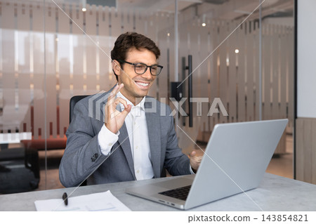 Smiling businessman making okay gesture during video call Smiling businessman making okay gesture during video call 143854821
