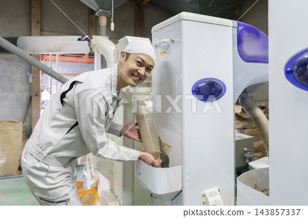 一位稻農在水稻收割後勞動,直視鏡頭。 一位稻農在水稻收割後勞動,直視鏡頭。 143857337