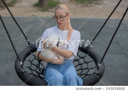 A woman is swinging on a swing while out for a walk with her cat. A woman is swinging on a swing while out for a walk with her cat. 143859088