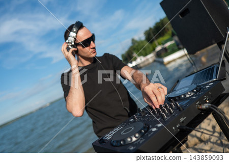 Male DJ playing music on the beach. Male DJ playing music on the beach. 143859093