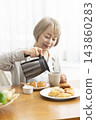 A senior woman's breakfast of freshly baked bread 143860283