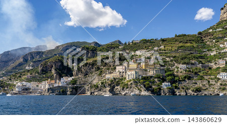 View of beautiful Amalfi town, Campania, Italy. Amalfi coast is most popular travel and holiday destination in Europe. Amalfi cityscape on coast line of mediterranean sea - view from sea View of beautiful Amalfi town, Campania, Italy. Amalfi coast is most popular travel and holiday destination in Europe. Amalfi cityscape on coast line of mediterranean sea - view from sea 143860629