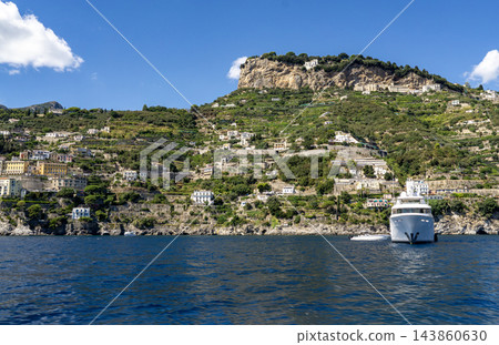 View of beautiful Amalfi town, Campania, Italy. Amalfi coast is most popular travel and holiday destination in Europe. Amalfi cityscape on coast line of mediterranean sea - view from sea View of beautiful Amalfi town, Campania, Italy. Amalfi coast is most popular travel and holiday destination in Europe. Amalfi cityscape on coast line of mediterranean sea - view from sea 143860630