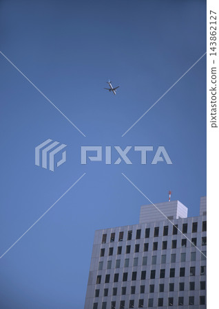 一架飛機飛越新宿西口的摩天大樓,前往羽田機場。 一架飛機飛越新宿西口的摩天大樓,前往羽田機場。 143862127