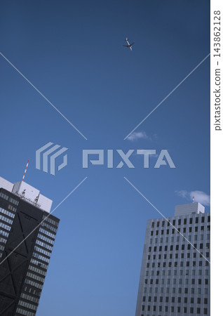 一架飛機飛越新宿西口的摩天大樓,前往羽田機場。 一架飛機飛越新宿西口的摩天大樓,前往羽田機場。 143862128