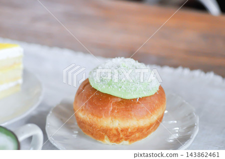 brioche donut or doughnut or bun with green tea dressing or pandan custard and Coconut flakes topping brioche donut or doughnut or bun with green tea dressing or pandan custard and Coconut flakes topping 143862461