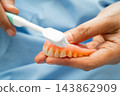Asian senior woman patient clean teeth denture with toothbrush for chew food. 143862909
