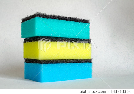 Three stacked kitchen sponges with colored foam and black scrub pads Three stacked kitchen sponges with colored foam and black scrub pads 143863304