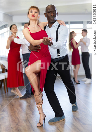 African man and woman dancing tango in couple during lesson at studio African man and woman dancing tango in couple during lesson at studio 143863911
