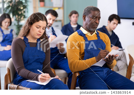 Workers of different ages listen attentively to the teacher and take notes in notebooks during a lecture at learning center 143863914