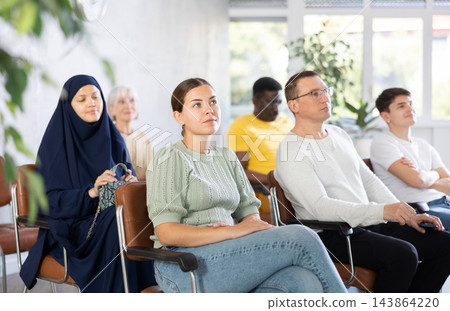 Young woman listening to lecture while sitting on chair in office Young woman listening to lecture while sitting on chair in office 143864220