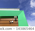 A surveillance camera and a loudspeaker on a building facade against a blue sky. 143865464