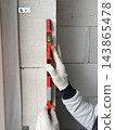 A builder checks the level of an aerated concrete wall using a spirit level. Construction and renovation concept 143865478