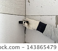 A worker measures a concrete block wall with a laser distance meter. Interior renovation, building measurement 143865479
