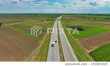 Aerial view of highway crossing green agricultural fields 143865920