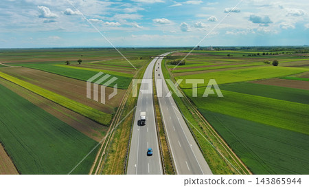 Aerial view of highway crossing green agricultural fields 143865944