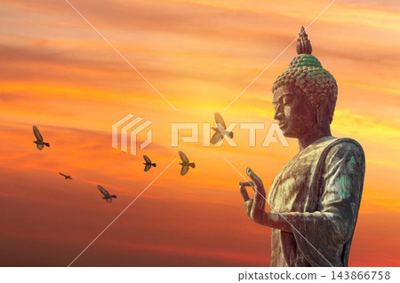 Bronze Buddha statue with flying birds at sunset sky background Bronze Buddha statue with flying birds at sunset sky background 143866758