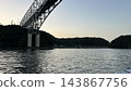 一座橋橫跨傍晚的天空和水面。 143867756
