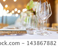Elegant restaurant table setting with wine glasses and warm bokeh lights 143867882