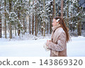 Profile of a teenage girl with long hair and snow on her hair clip and scarf standing by a snowy forest road. Concept of calm winter reflection, teen mindfulness and a peaceful moment in nature. 143869320