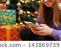 Woman using smartphone near Christmas tree and presents 143869739
