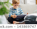Young boy using nebulizer while playing with tablet at home 143869747